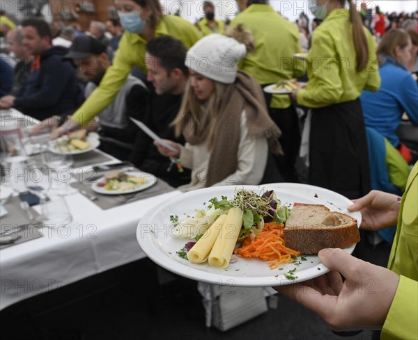 Service staff with starter plate of mixed salad with sliced cheese and sprouts