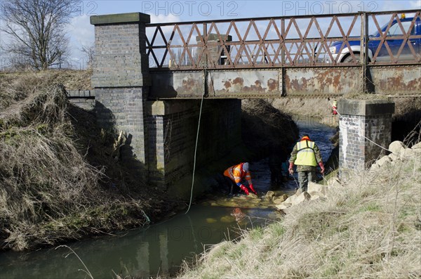 Men building fish pass underneath bridge on river