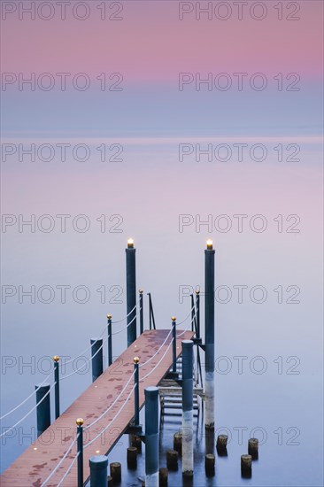 Rosa Abendstimmung ueber dem Bodensee mit beleuchtetem Badesteg zum See