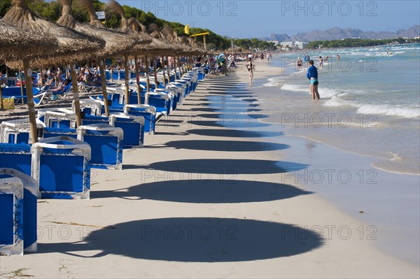 Shadows of beach umbrellas and tourists on sandy beach