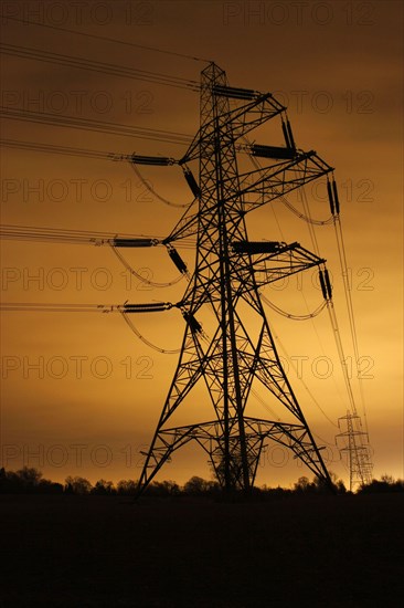 Electricity pylon and overhead power lines illuminated at night by light pollution in the city of Leicester
