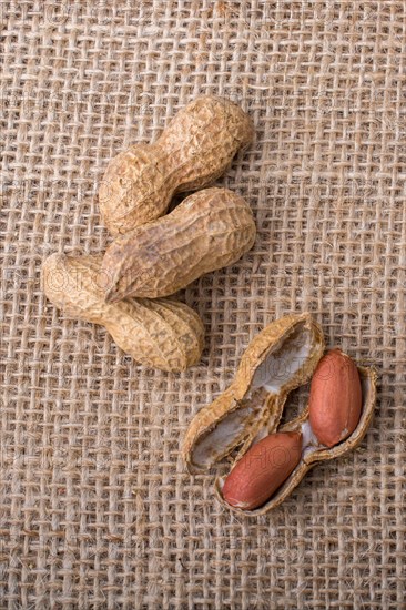 Cracked open peanuts with shell on a linen canvas background