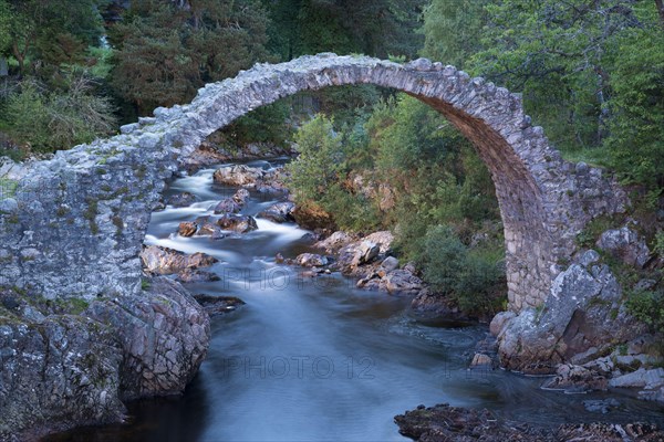 Old packhorse bridge over river at dusk