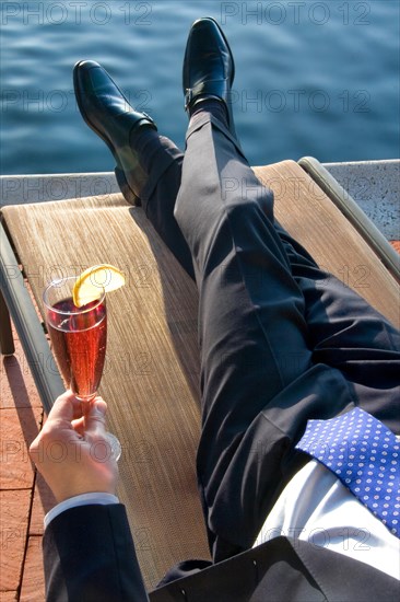 Executive relaxing by the pool with a drink in his hand