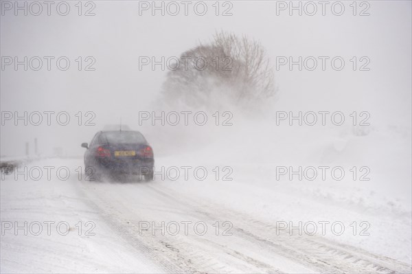 Car driving on a country road during a heavy snowstorm