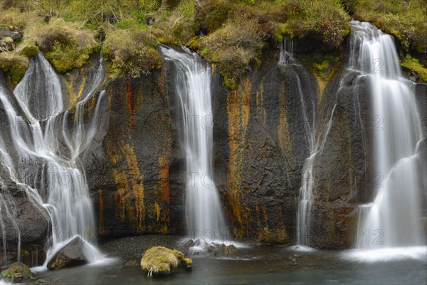 Cascades and waterfalls flowing from the lava field into the river