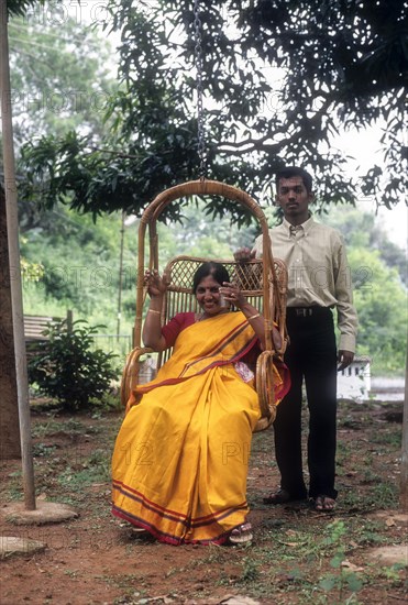 Mother sitting in hanging cane chair and her son standing nearby at Singara