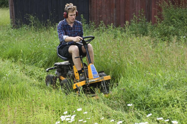 Man with ride-on mower on farm