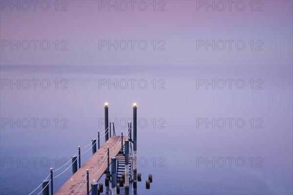 Rosa-violette Abendstimmung ueber dem Bodensee mit beleuchtetem Badesteg zum See