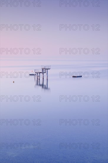 Rosa-violette Abendstimmung ueber dem Bodensee mit Blick zum Sprungturm und den Flossen der Freibadanlage Horn inmitten des Sees