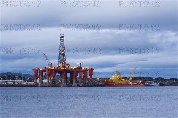 Oil rig moored in sea near coast at dusk