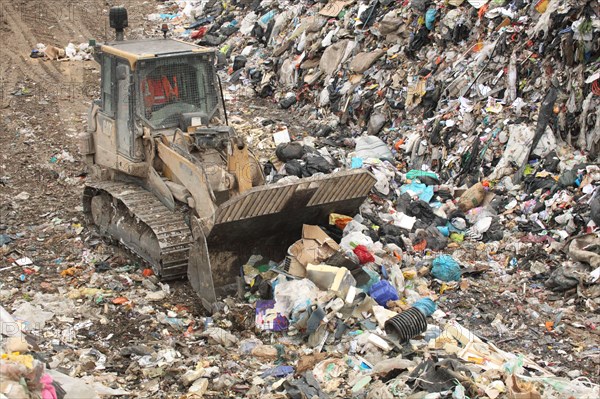 Bulldozer moving rubbish on landfill tip