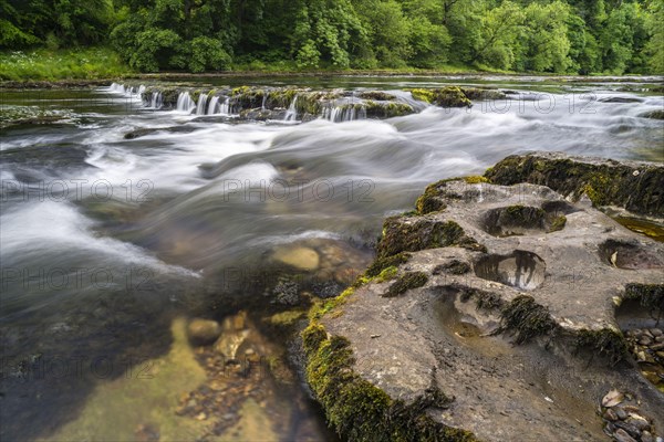 View of eroded rocks beside river and waterfall