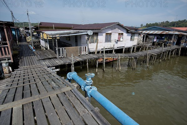 Walkway with blue hookah and huts on stilts in the river