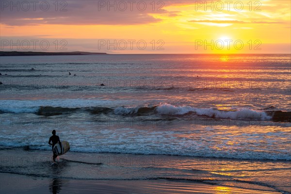 Man with surfboard rushing into water at Strandhill. Sligo