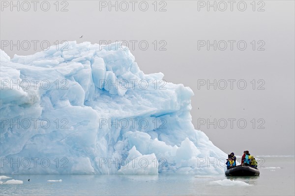 Tourists photographing iceberg from Zodiac inflatable boat