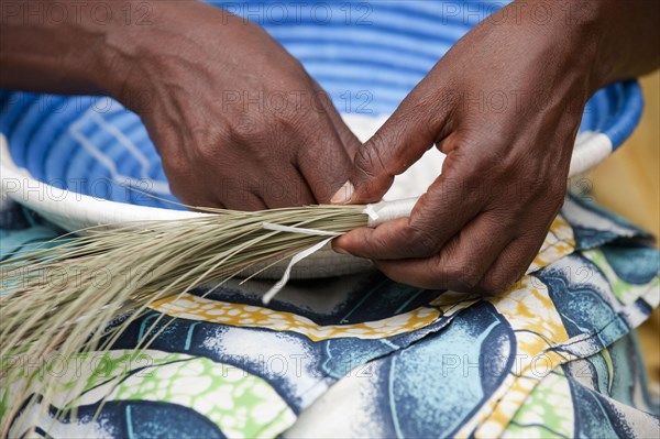 Close-up of a lady weaving a traditional basket at the Ladies' Cooperative