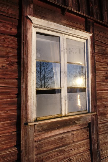 Altes Sprosssenfenster in roter Blockhausfassade