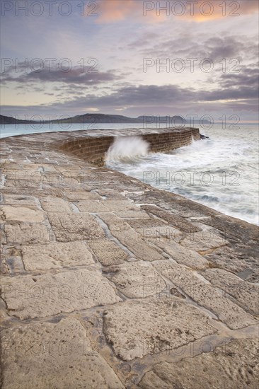 View of the harbour wall with the waves breaking at sunrise