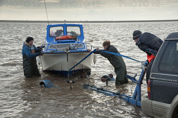 Licensed cockle pickers landing boat and unloading after picking from cockle beds