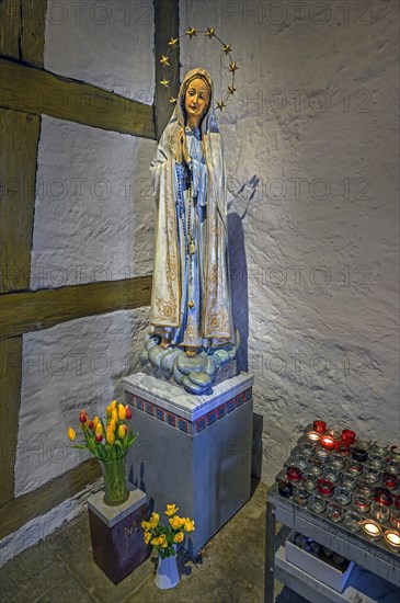 Figure of Mary with floral decoration and offering candles