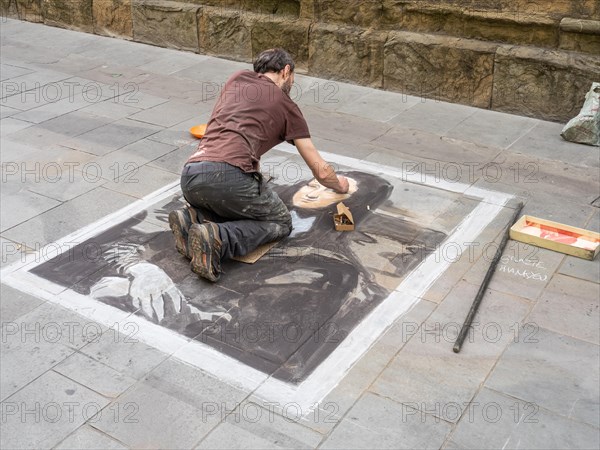 Strassenkuenstler malt das Bild Mona Lisa von Leonardo da Vinci mit Kreide auf den Asphalt