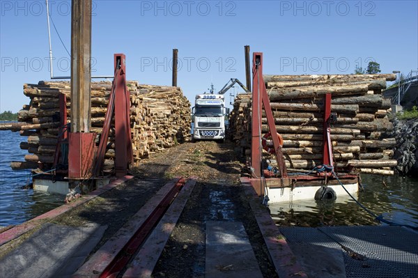 Lorry with grapple loading logs onto timber barge