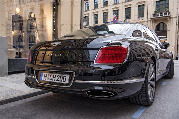 Parked luxury sedan Bentley Flying Spur First Edition in front of fashion shop Boutique Dior