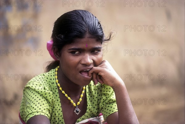 Betta Kurumba belle sitting in front of her hut