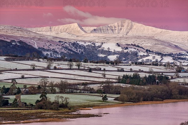 View of snow covered farmland and hills at sunrise