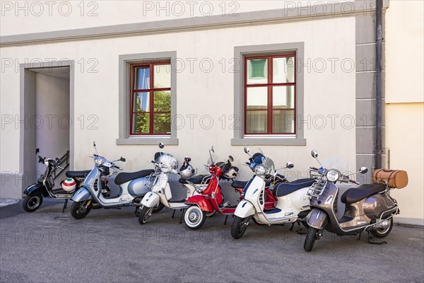 Alte und moderne Vespa Roller vor Hauswand