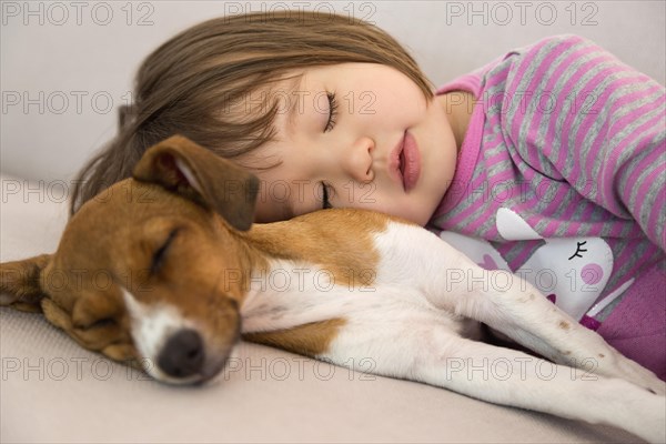 Toddler girl sleeping next to mixed terrier puppy dog