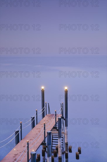 Rosa-violette Abendstimmung ueber dem Bodensee mit beleuchtetem Badesteg zum See