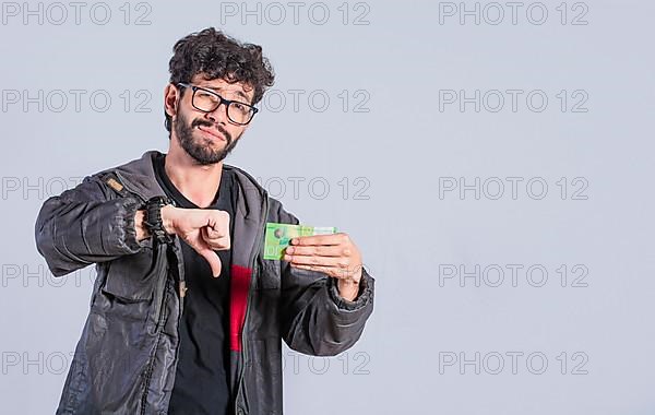 Concept of a person with money problems. Unhappy person with a Nicaraguan banknote with his thumb down