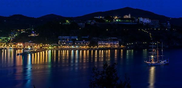 Panoramic view of Porto Azzurro with illuminated harbour promenade in evening mood during blue hour