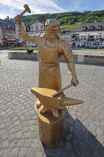 Golden sculpture as goldsmith and locksmith working steel at an anvil with hammer in Alf