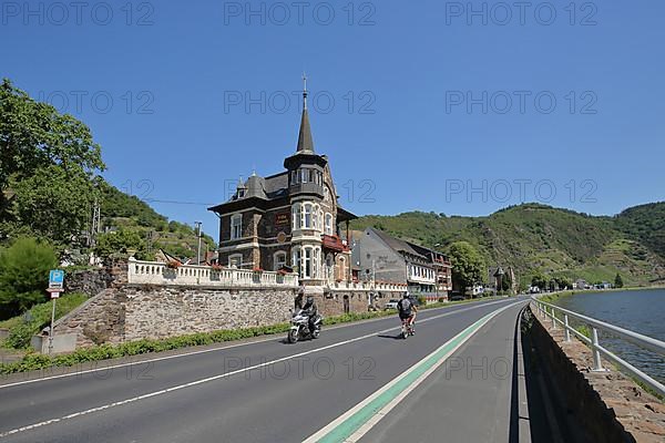 Villa Cornely with motorcyclist and cyclist on the road in Treis-Karden on the Lower Moselle