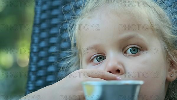 Little girl eat french fries. Close-up of blonde girl takes potato chips with her hands and tries them sitting in street cafe on the park. Odessa