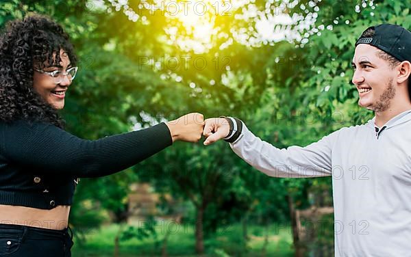 Two young teenage girls bumping their fists outdoors