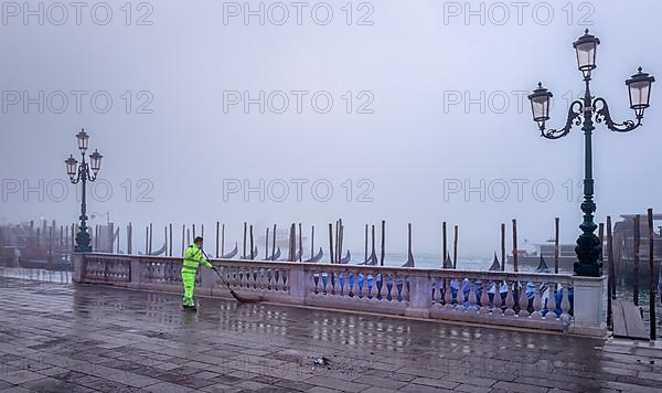 City cleaning staff in the morning fog at the gondola harbour in front of St. Mark's Square