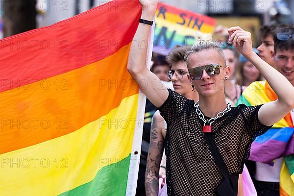 Young homosexual man carrying rainbow flag at CSD parade