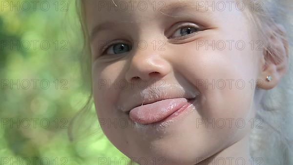 Portrait of cute little girl sticking her tongue out and smiling after eating delicious ice cream. Extreme close-up portrait of little girl. Odessa Ukraine