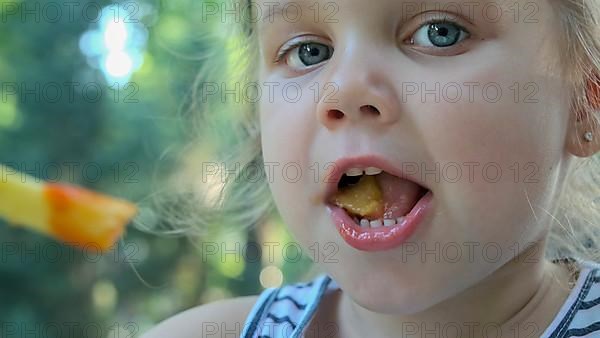 Little girl eat french fries. Close-up of blonde girl takes potato chips with her hands and tries them sitting in street cafe on the park. Odessa Ukraine