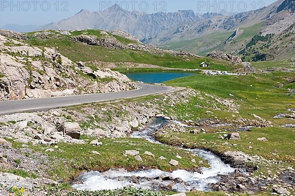 View of alpine plateau with Lac des Eissaupres next to mountain road from Route de Col de la Bonette e Restefond