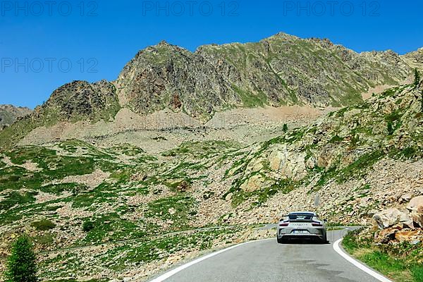 Porsche GT3 sports car crosses 2350-metre Passo Lombarda pass above tree line on French-Italian border