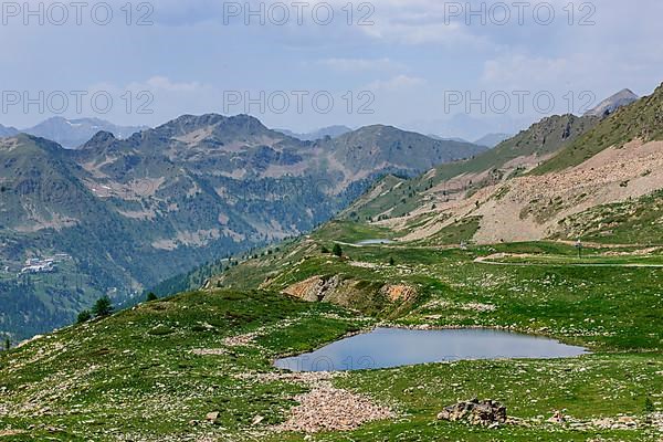 View of small mountain lake above tree line next to 2350 metre high Passo Lombarda pass at French-Italian border