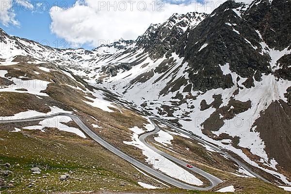 Red sports car Porsche drives into serpentine hairpin bend from Alpine pass on Timmelsjoch-Hochalpenstrasse