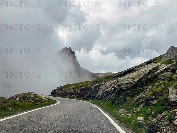 Dense cloud Wall of clouds pushes over high narrow mountain road above tree line