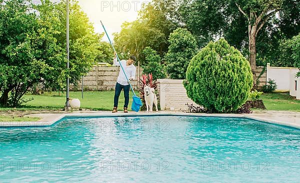 Man cleaning a swimming pool with skimmer