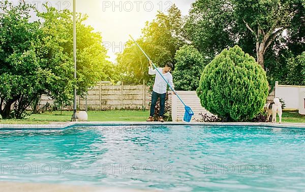 Maintenance person cleaning a swimming pool with skimmer